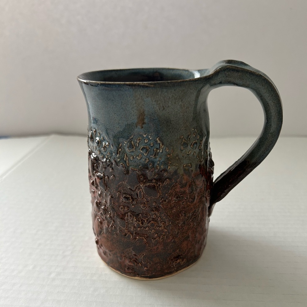 This item is a handmade ceramic pottery mug textured spot for thumb